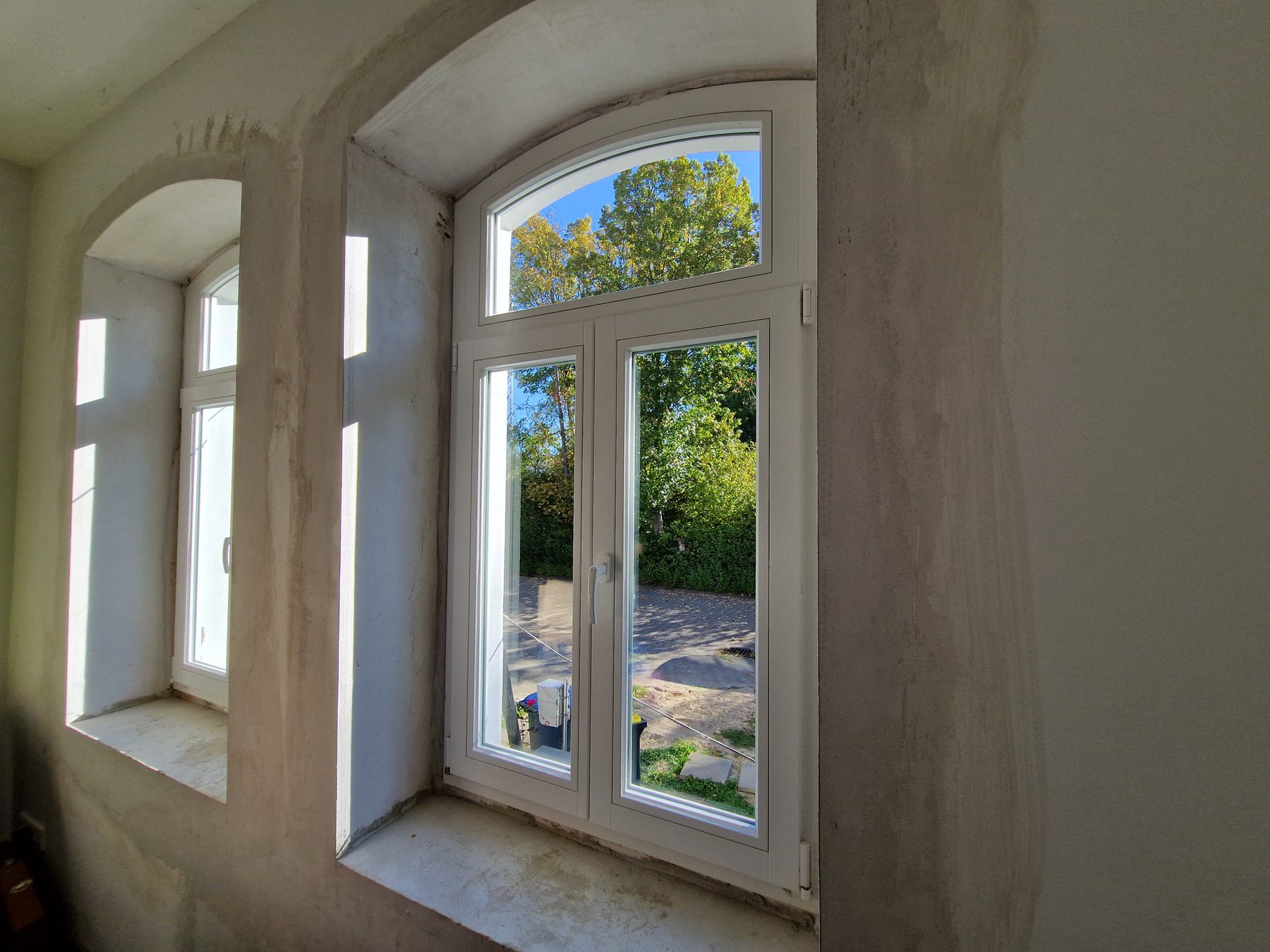 Neue Rundbogenfenster in tiefen, frisch verputzten Laibungen