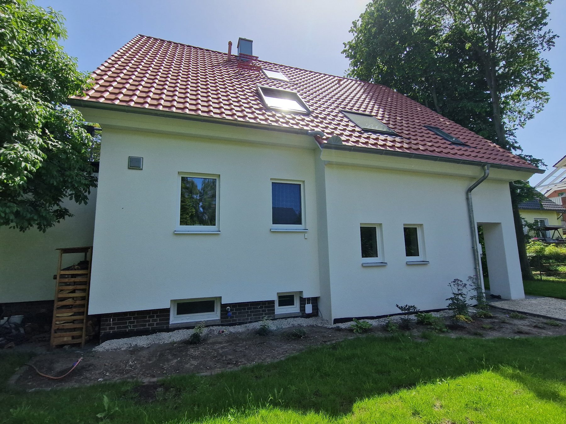 Dasselbe Einfamilienhaus nach der Komplettsanierung, hell verputzt mit neuem Dach